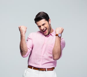 Happy young man celebrating his success over gray background-1